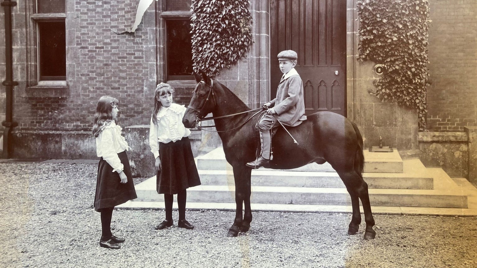 Ralph Dutton on a horse with his sisters Blanche and Ursula outside the house, 1905