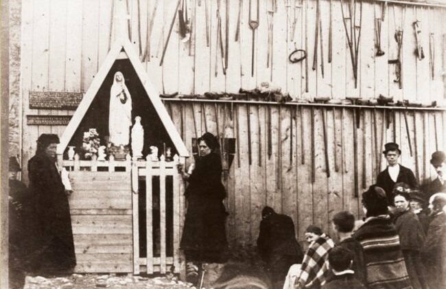 Pilgrims praying at the apparition gable of Knock church in 1880, with crutches left at the wall