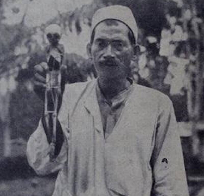 A man in Indonesia holding a fake orang pendek skeleton, c. 1932